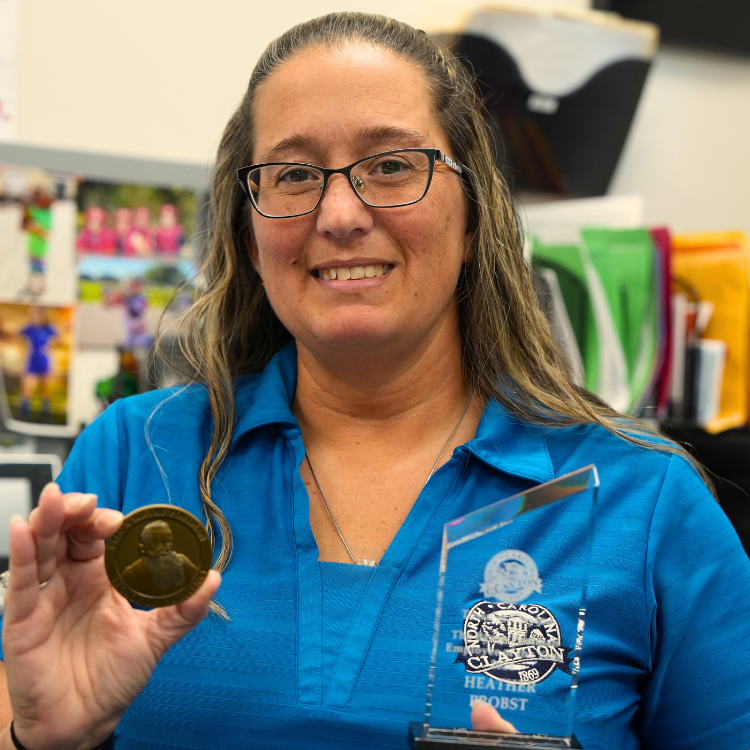 Heather Probst holds glass plaque  and commemorative coin